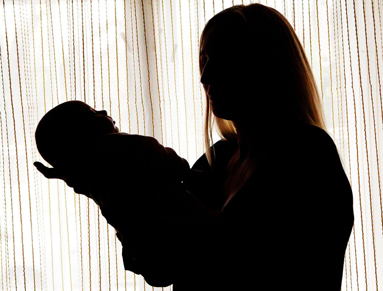 Женщина держит на руках ребенка, родившегося от украинской суррогатной матери в городе Ужгороде