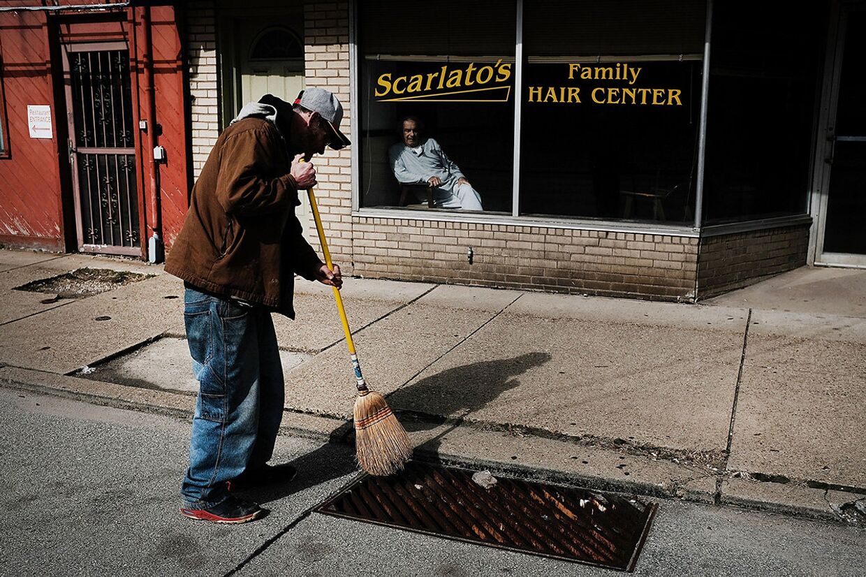 Безработный подметает улицу за вознаграждение в городе Клэртон, штат Пенсильвания