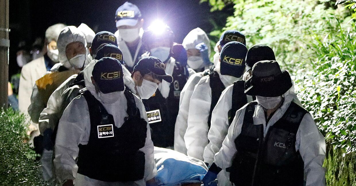 Сотрудники полиции несут тело мэра Сеула Пак Вон Суна