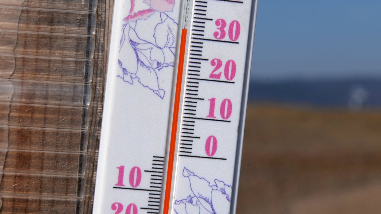 +32 градуса Цельсия на солнце показывает термометр на стене зимнего передвижного рыбацкого домика на берегу реки Енисей в окрестностях Красноярска
