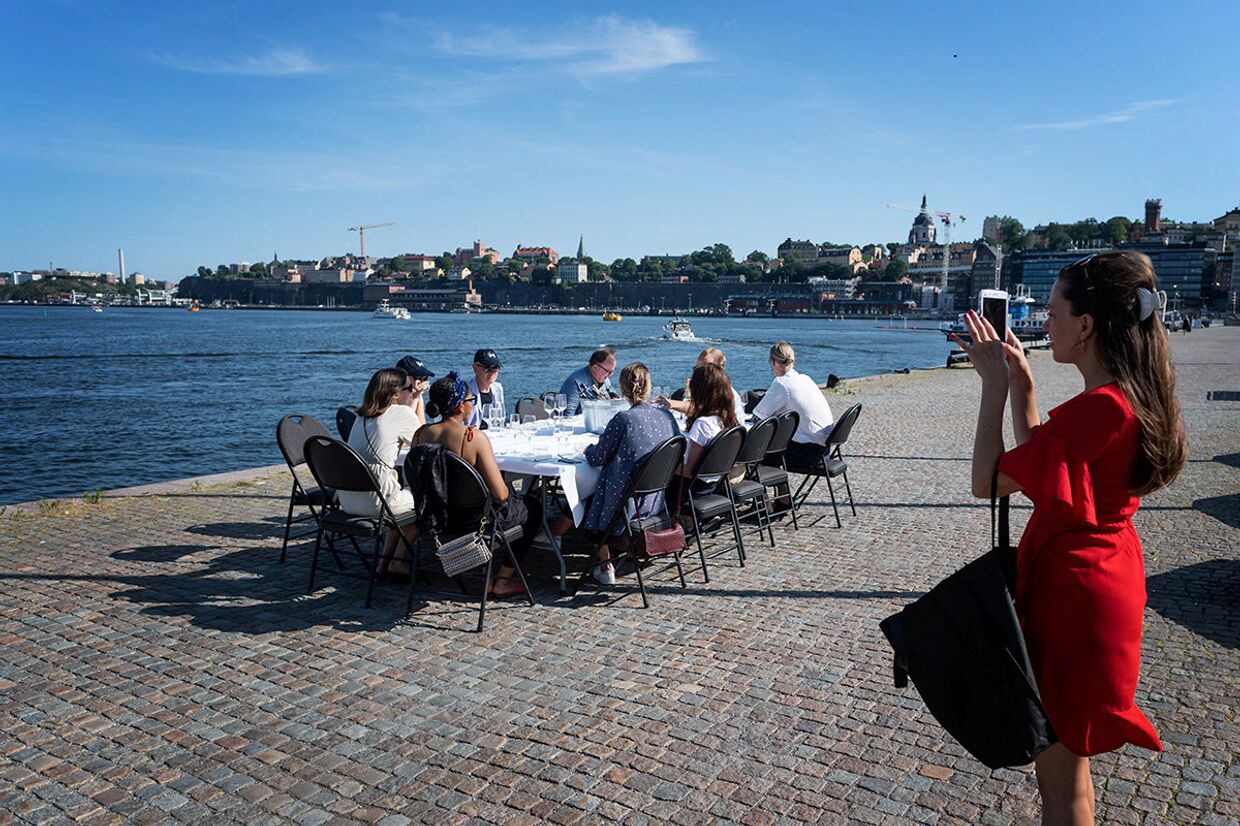 Отдыхающие за столом на набережной в Стокгольме