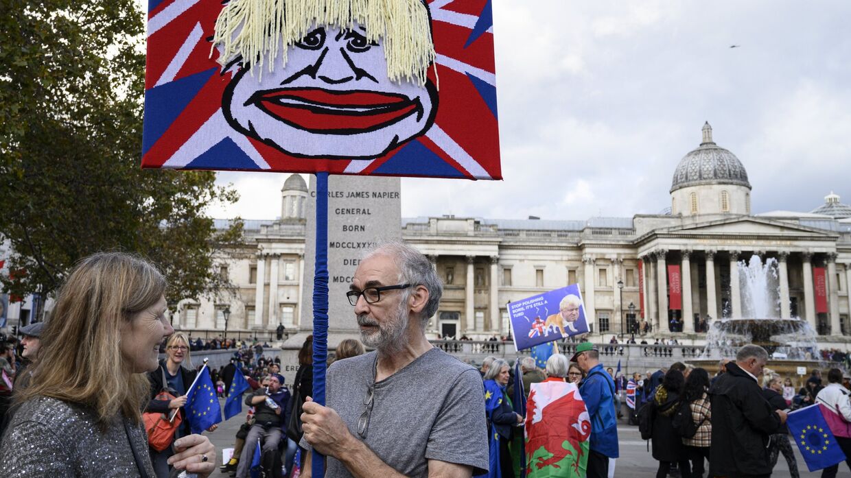 Участники акции против Brexit в Лондоне держат плакат с изображением Бориса Джонсона