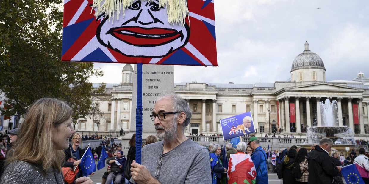 Участники акции против Brexit в Лондоне держат плакат с изображением Бориса Джонсона