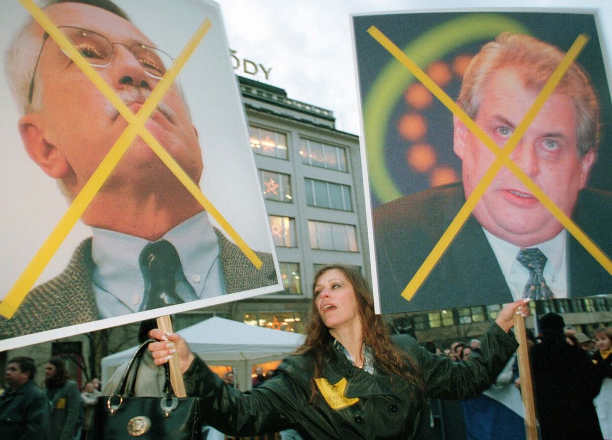 Женщина держит плакат портретами Вацлава Клауса и Милоша Земана во время митинга на Вацлавской площади в Праге