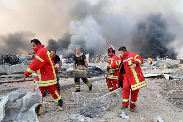 Спасатели выносят раненого на месте взрыва в Бейруте, Ливан