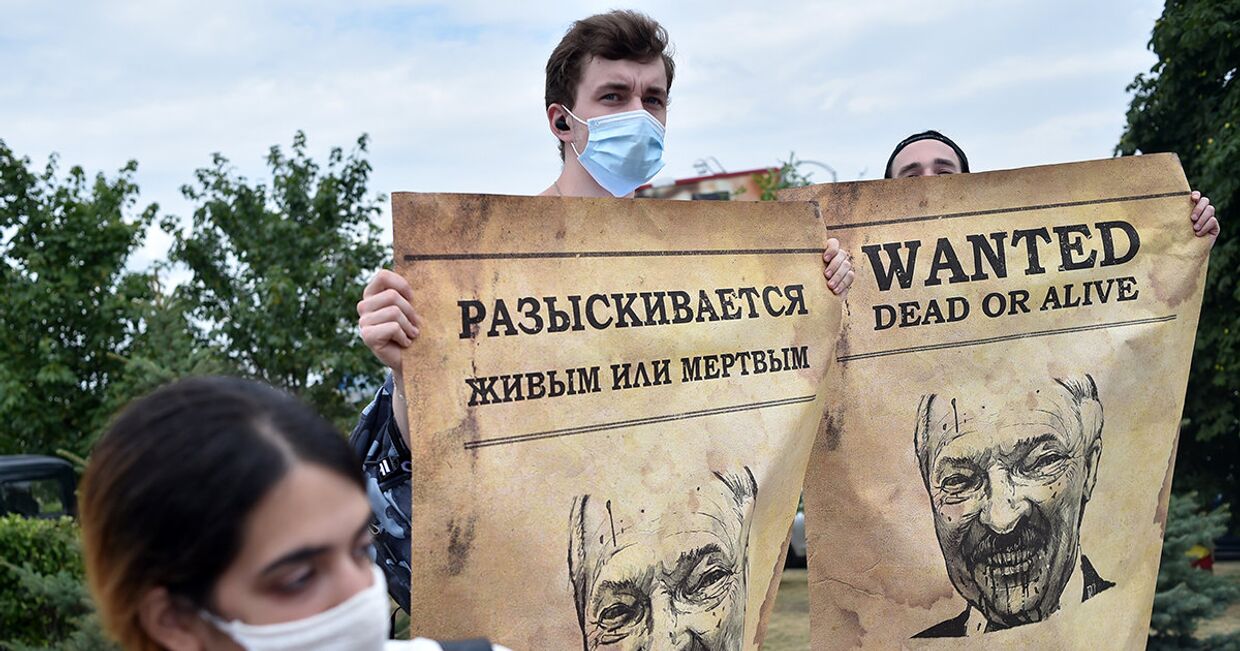 Люди с плакатами, изображающими президента Белоруссии Александра Лукашенко во время акции протеста в Минске