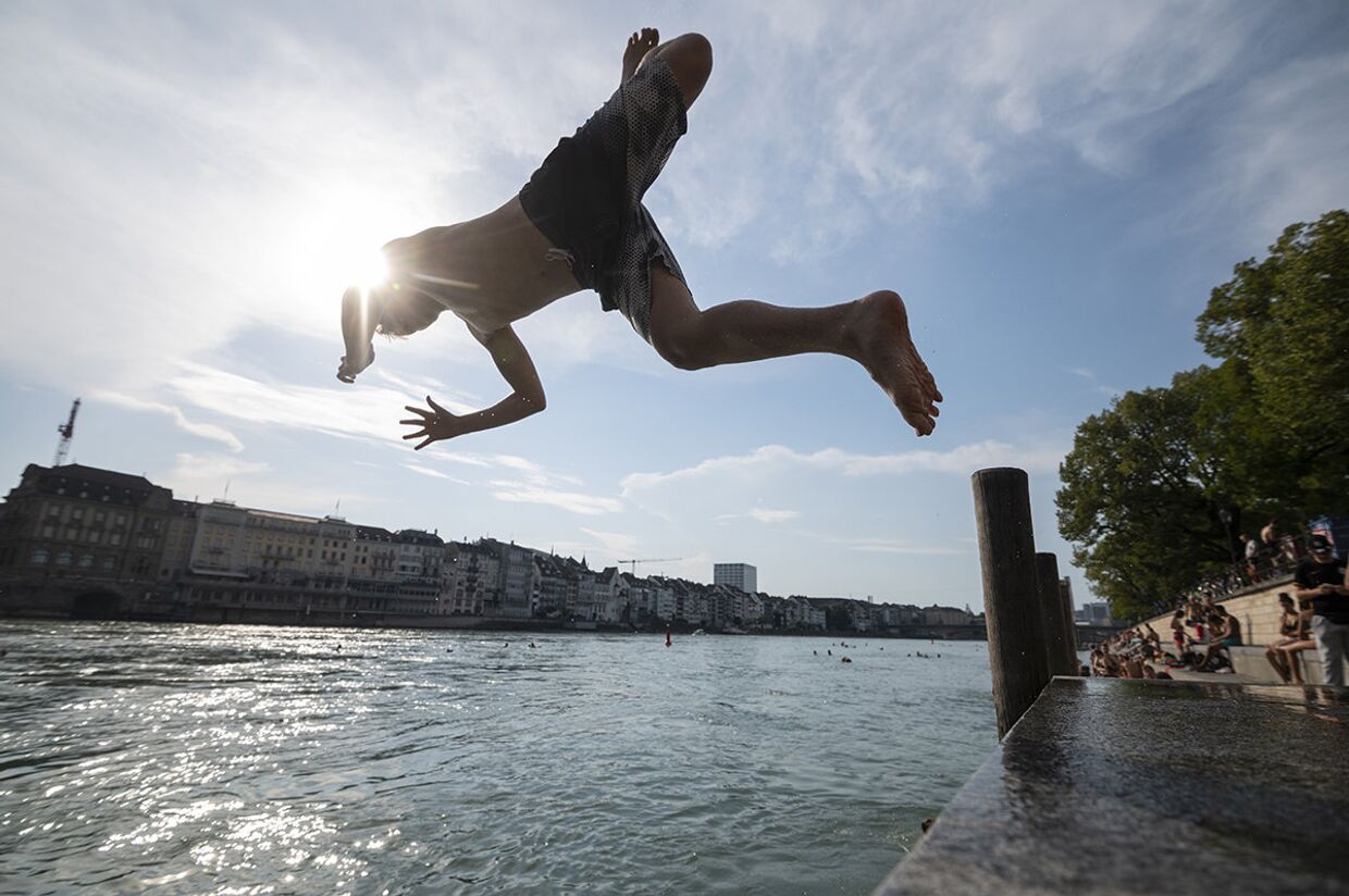 Юноша ныряет в реку Рейн в Базеле, Швейцария