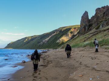 Участники экспедиции идут по берегу бухты Тетяева острова Уруп (остров южной группы Большой гряды Курильских островов). Участники экспедиции идут по берегу бухты Тетяева острова Уруп (остров южной группы Большой гряды Курильских островов).