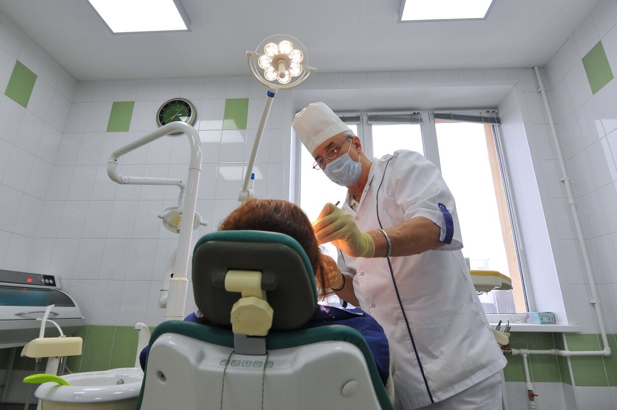 Хирург-стоматолог во время приема пациента
