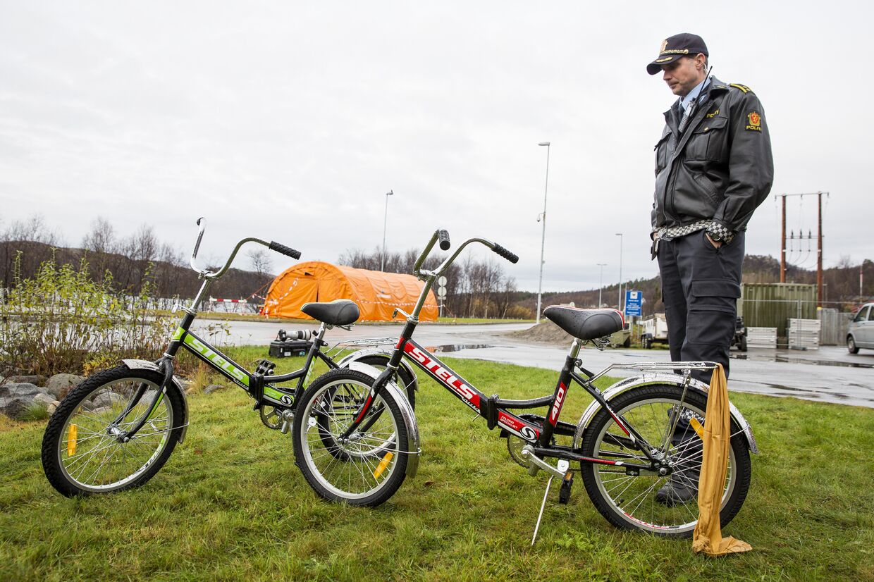 Офицер норвежской полиции осматривает велосипеды, которыми воспользовались желающие пересечь российско-норвежскую границу в Стурскуге