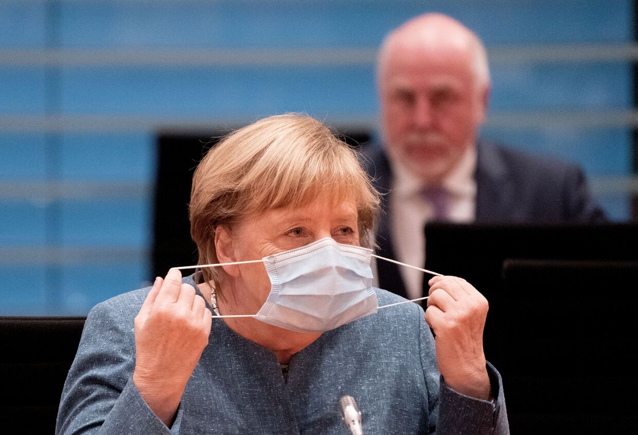 Канцлер Германии Ангела Меркель надевает защитную маску