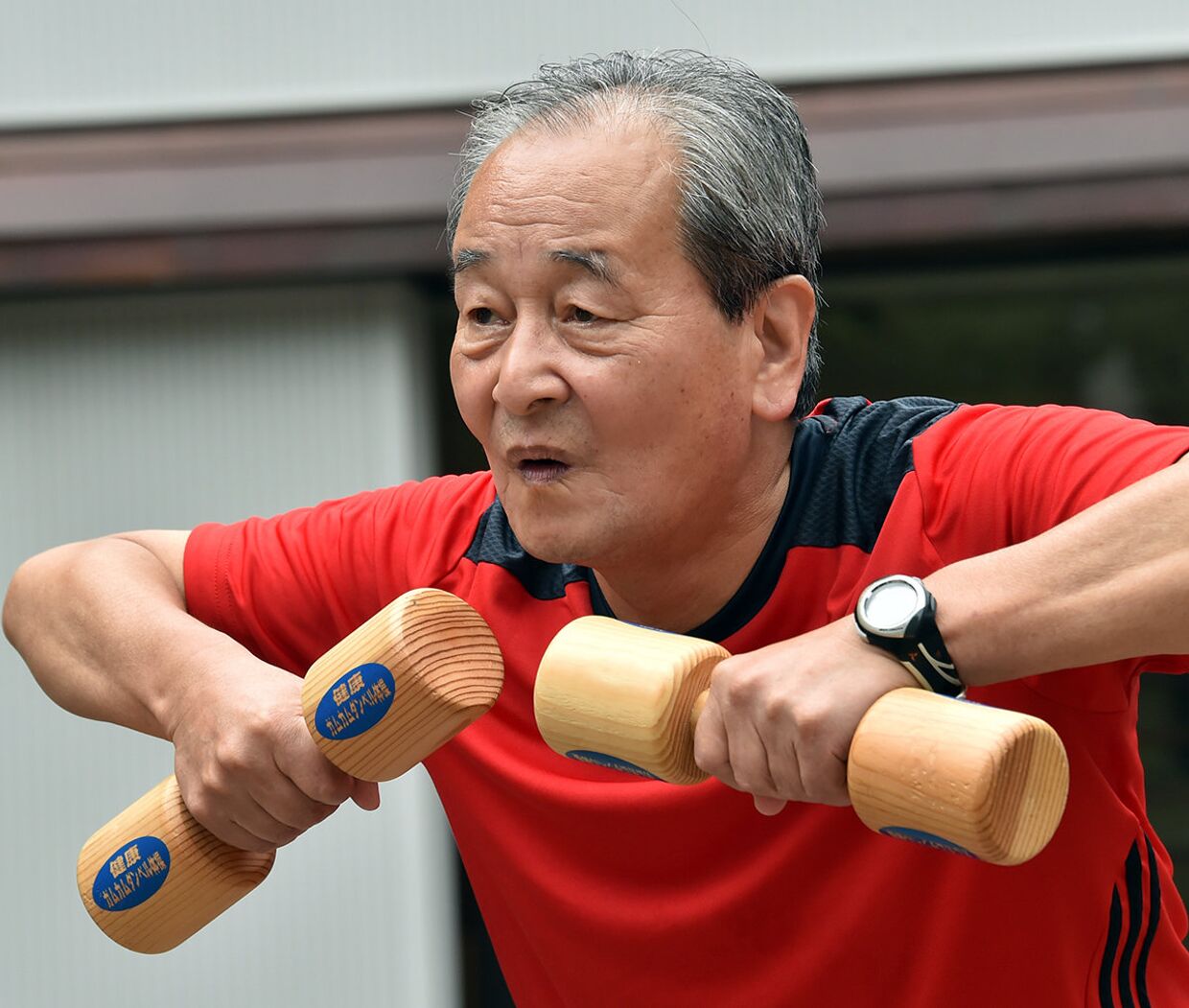 Пожилой мужчина во время занятий с деревянными гантелями в Токио