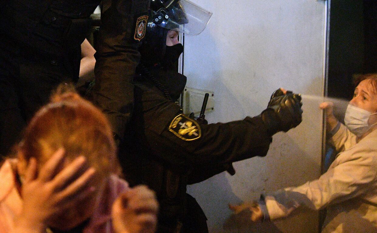 Сотрудник ОМОНа применяет баллончик со слезоточивым газом против участника акции протеста в Минске