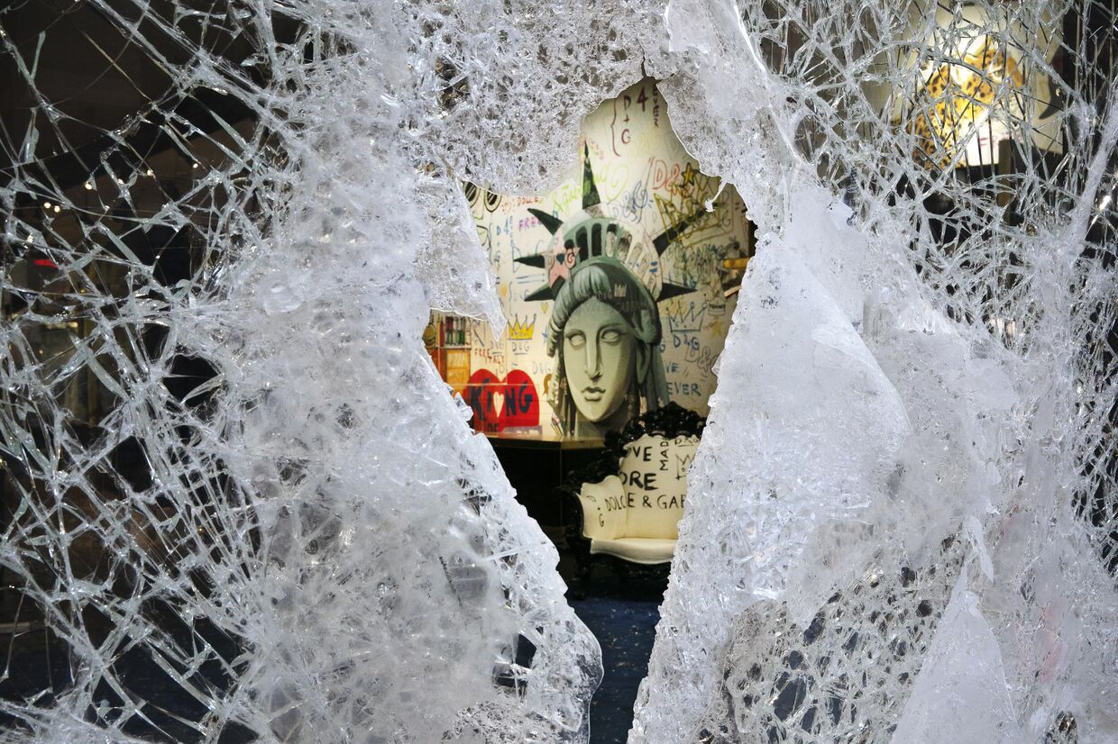 Граффити, изображающее лицо Статуи свободы, через разбитую витрину магазина в Нью-Йорке, США