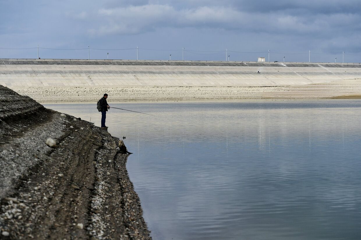 Мужчина ловит рыбу на берегу Аянского водохранилища в Крыму