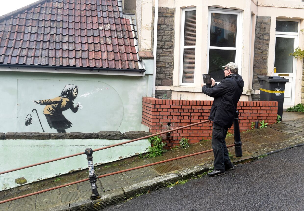 Мужчина фотографирует новую работу Бэнкси «Апчхи», Бристоль, Великобритания