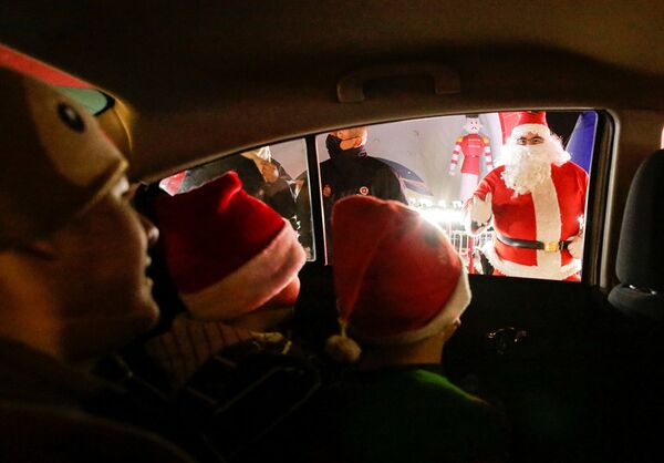 Дети приветствуют Санта-Клауса из автомобиля в Сьюдад-Хуаресе, Мексика