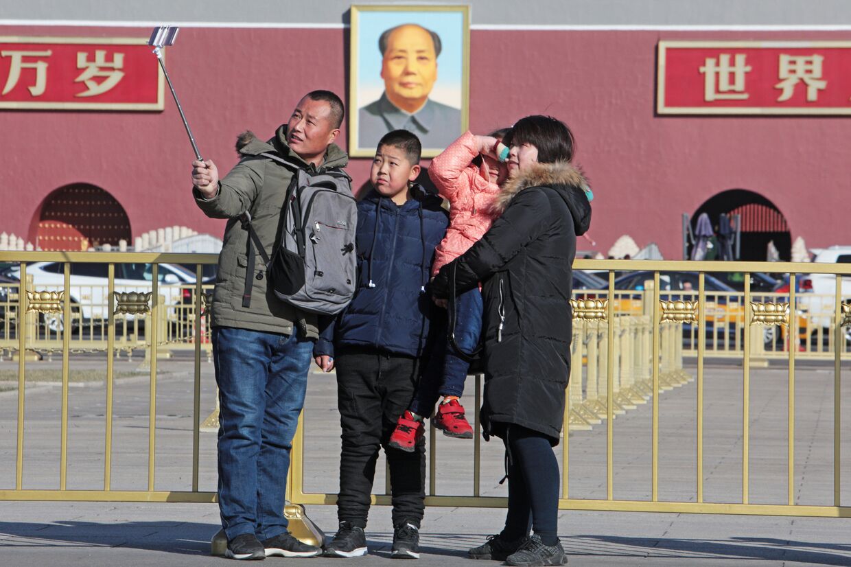 Семья фотографируется у портрета Мао Цзэдуна на центральной площади Пекина - Тяньаньмэнь