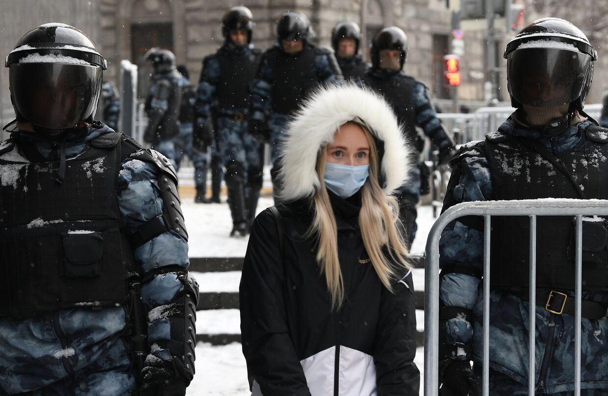Жительница Москвы идет по Пушечной улице, огороженной сотрудниками правоохранительных органов перед началом несанкционированной акции сторонников Алексея Навального