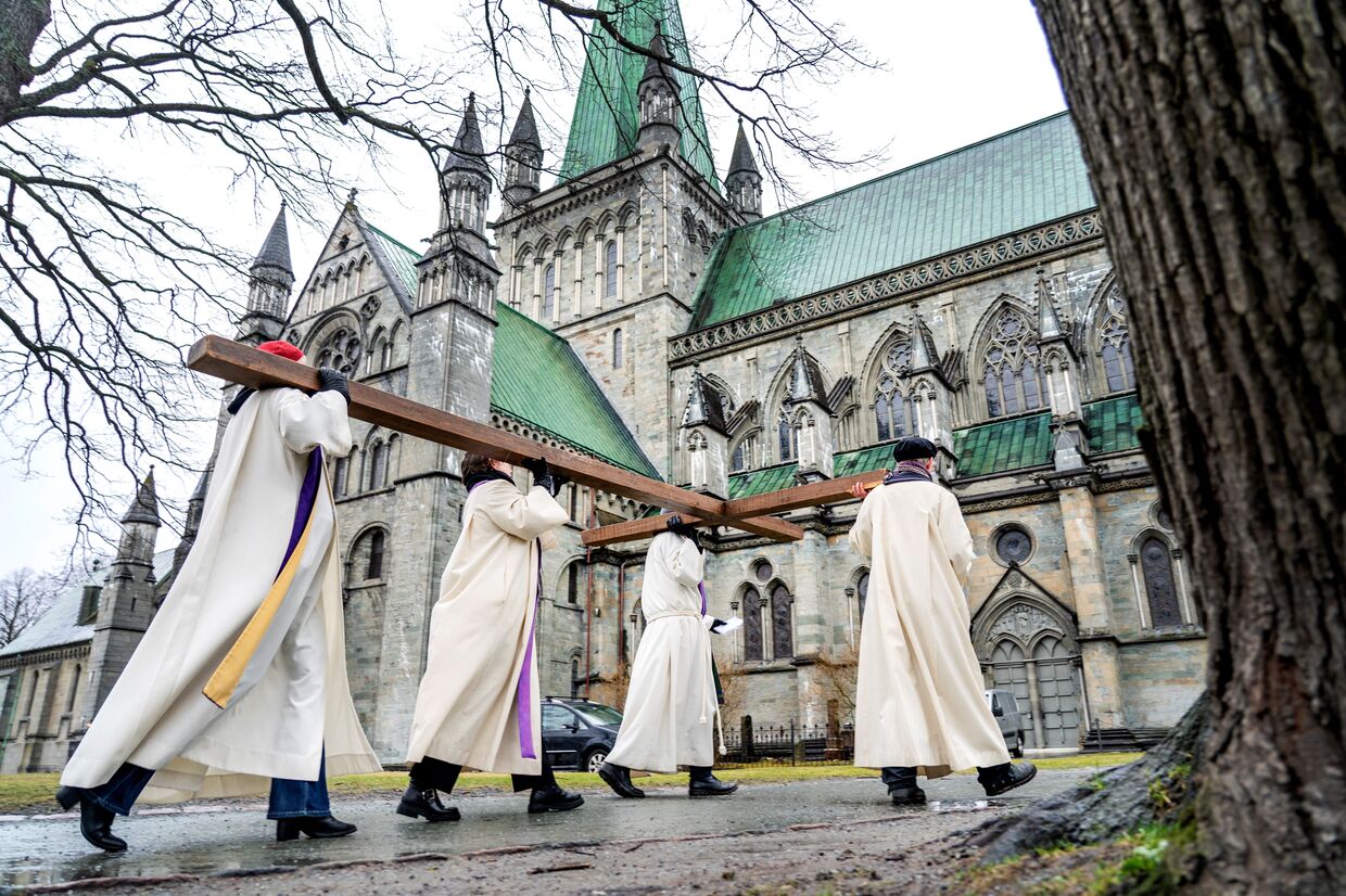 Священнослужители несут крест в католический собор в Тронхейме, Норвегия, в Страстную пятницу