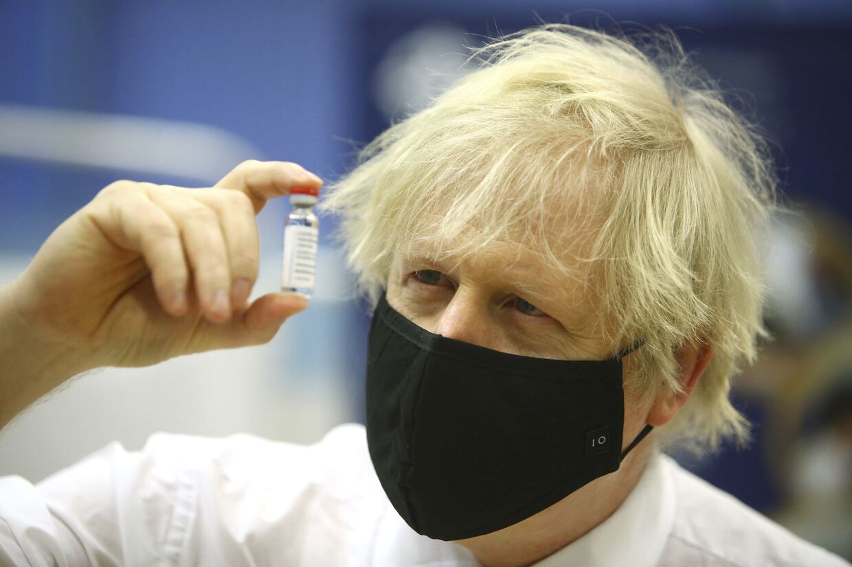 Премьер-министр Великобритании Борис Джонсон держит ампулу с вакциной от covid-19 производства AstraZeneca