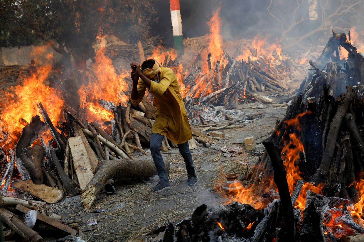 Мужчина среди рядов погребальных костров в крематории в Нью-Дели, Индия, где сжигают скончавшихся от covid-19