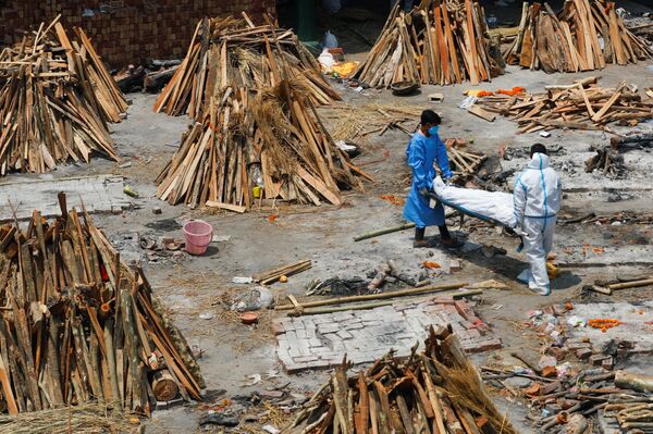 Сотрудники крематория в Нью-Дели, Индия, готовят место для сжигания тел умерших от covid-19