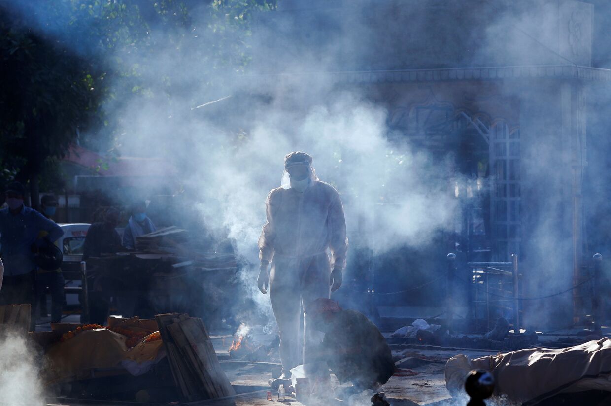 Член семьи человека, скончавшегося от коронавируса. Тело готовят к сжиганию в крематории в Нью-Дели, Индия