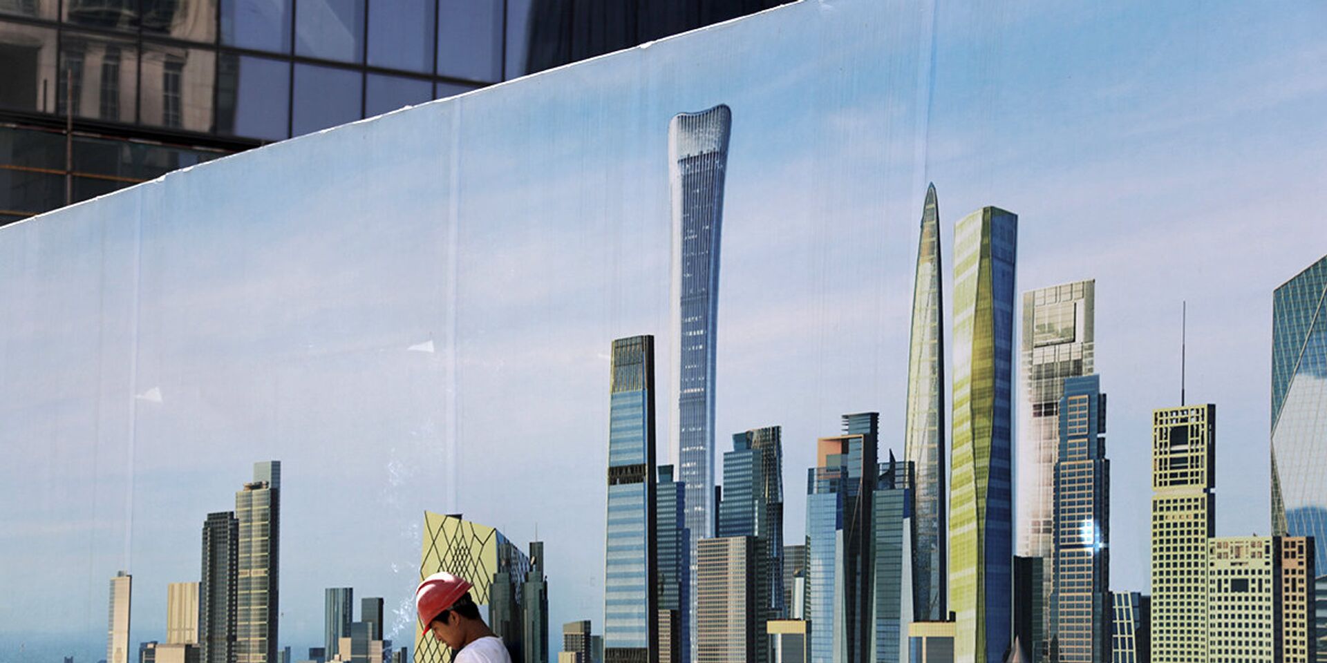 Рабочий у стены строительной площадки с изображением небоскребов в центральном районе Пекина - ИноСМИ, 1920, 29.06.2021