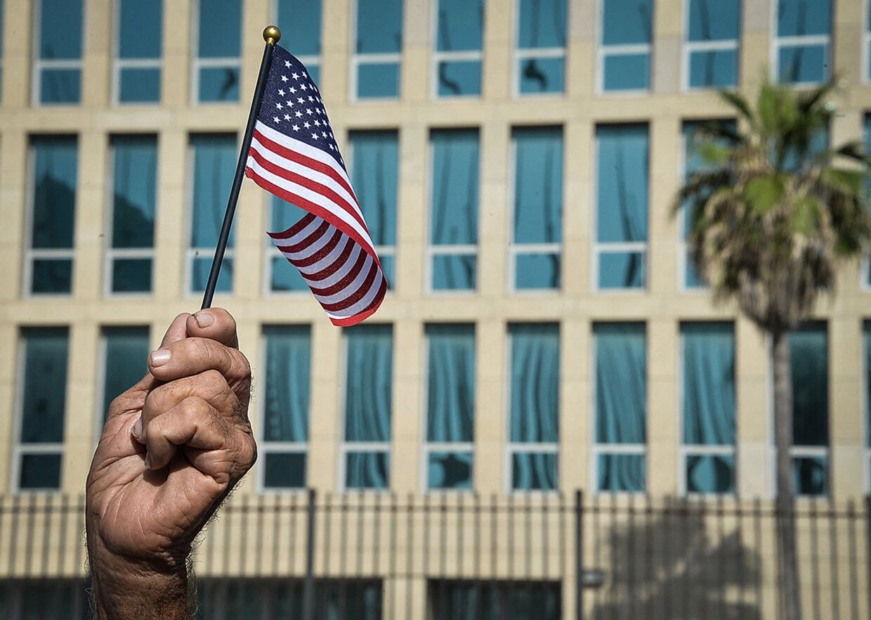 Американский флаг в руке кубинца у посольства США в Гаване