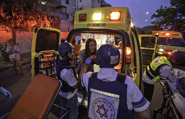 Спасатели эвакуируют женщину во время ракетного обстрела в Сдероте, Израиль