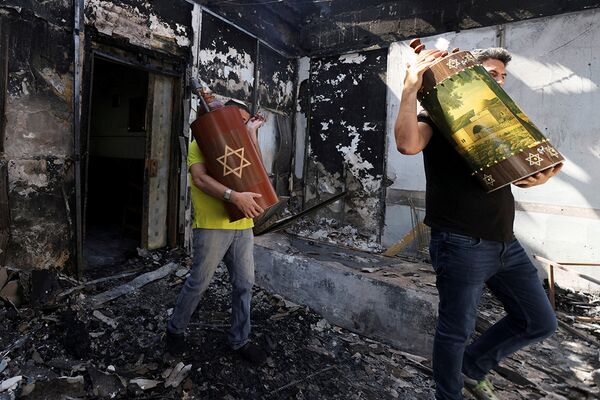 Евреи эвакуируют свитки Торы из сожженной синагоги в Лоде, Израиль