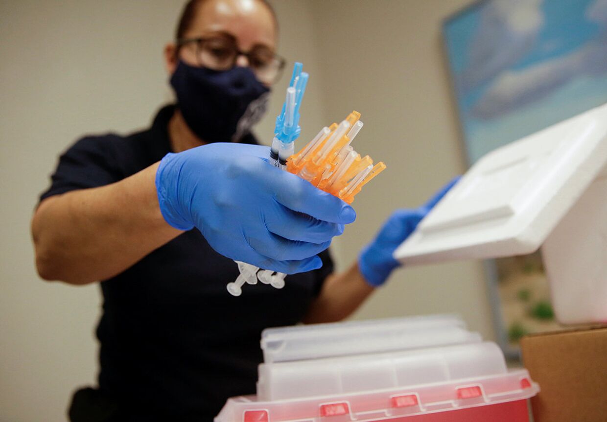 Медицинский работник держит шприцы с вакцинами Moderna и Pfizer