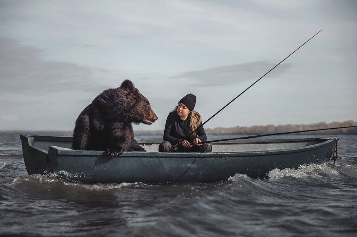 Русская женщина ловит рыбу в компании медведя