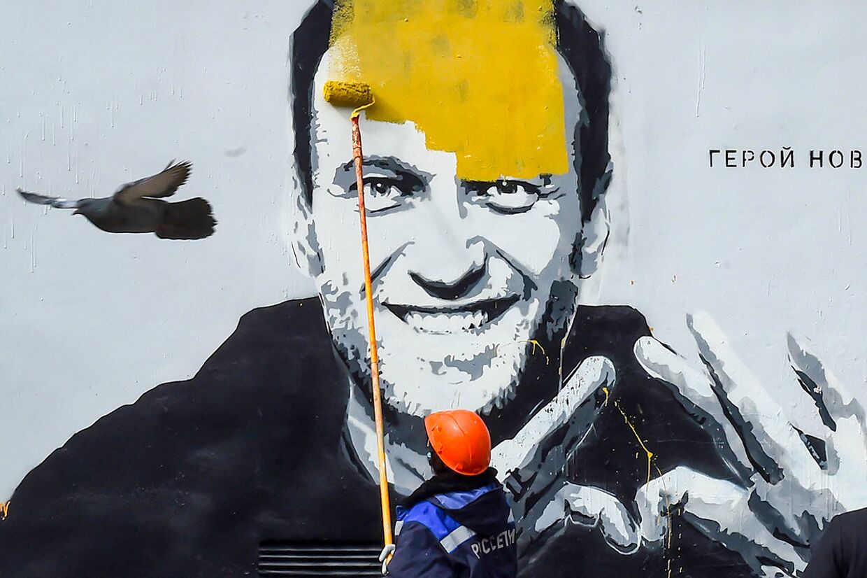 Рабочий закрашивает граффити с изображением Алексея Навального