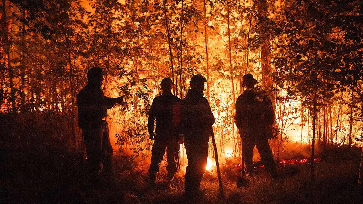 Россия. Пожарные посреди пламени возле села Кюёрелях
