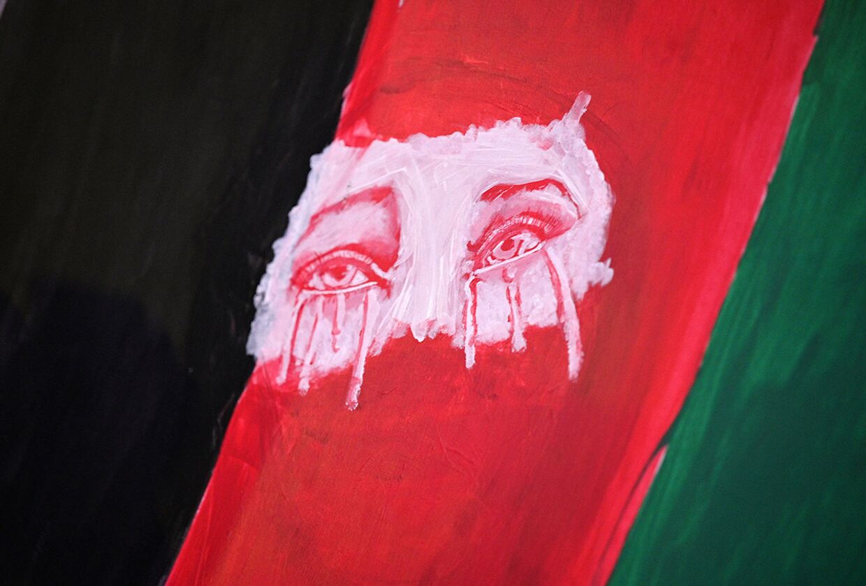 Заплаканные глаза на флаге Афганистана во время акции протеста
