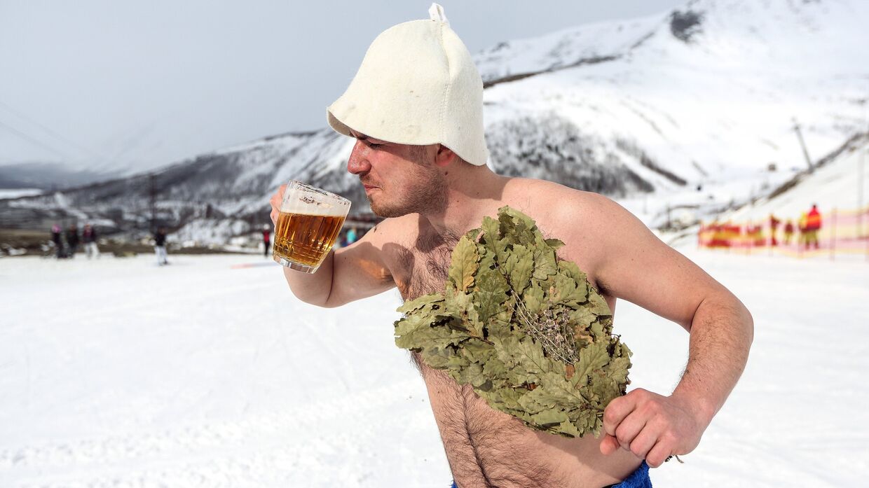 Сноубордист с банным веником и кружкой пива на горнолыжном склоне