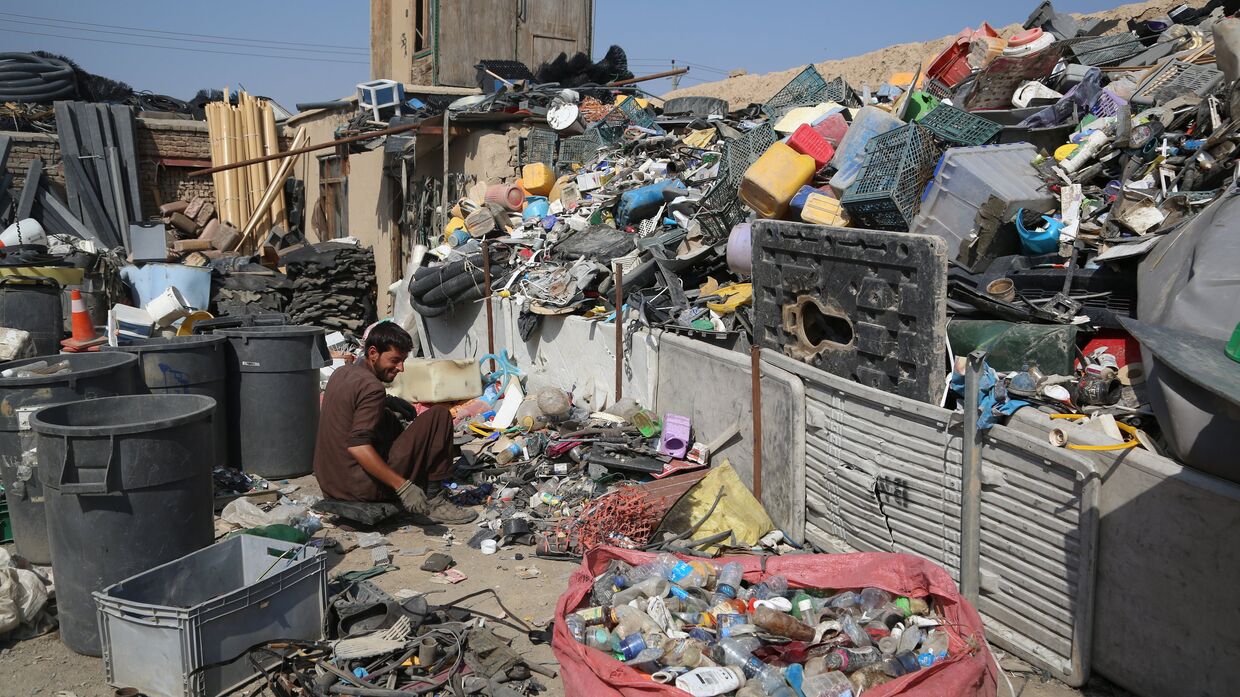 Афганец разбирает мусор, оставленный войсками США и НАТО