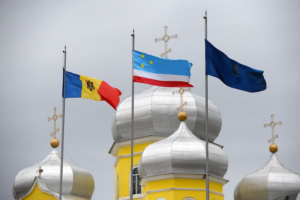 Флаги Молдовы и Гагаузии рядом с русской православной церковью в городе Комрат