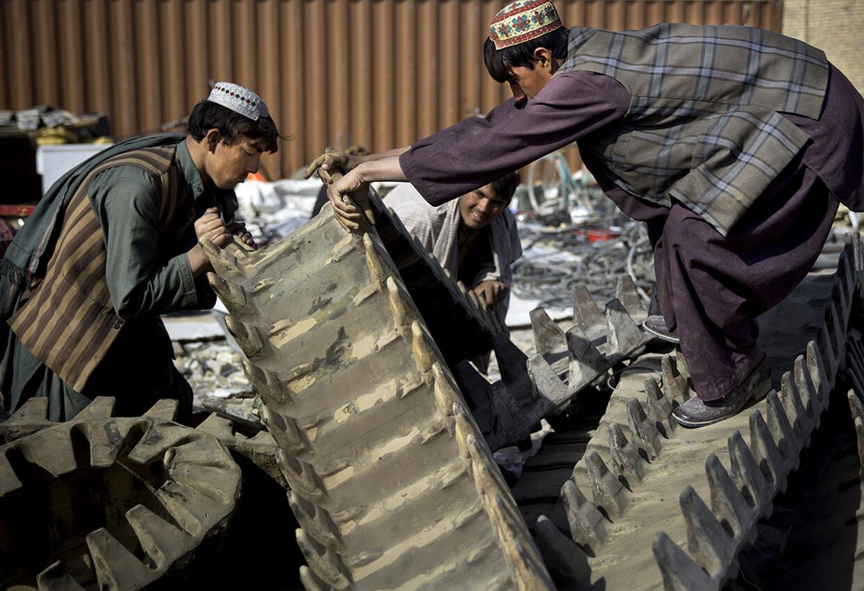 Афганские торговцы грузят резиновые гусеницы американского танка на юге Афганистана