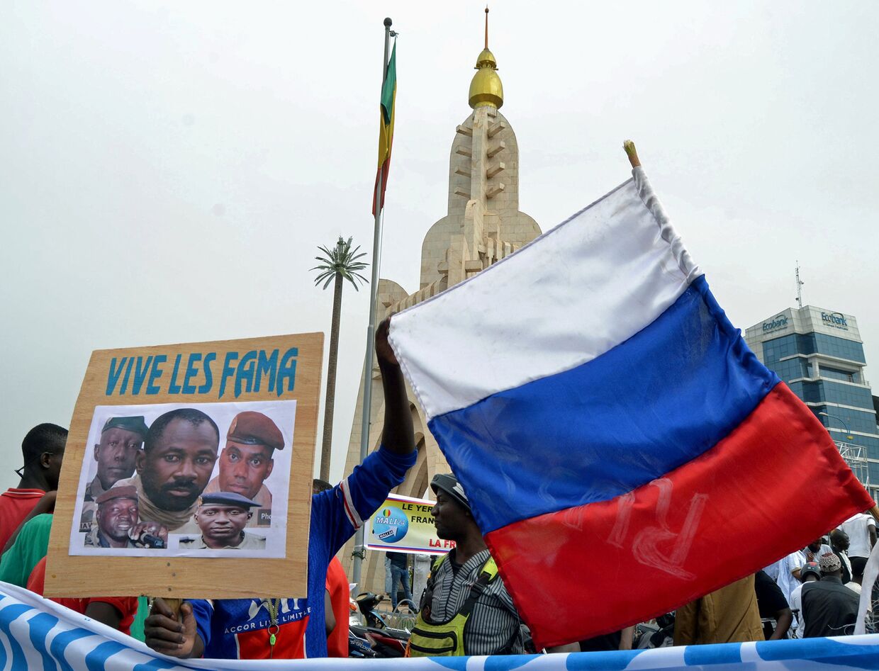 Малийцы держат фотографию полковника Ассими Гоиты и российский флаг