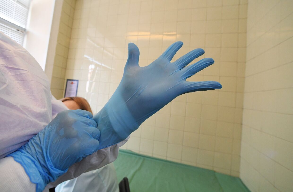 Врач надевает перчатки перед приемом пациентов