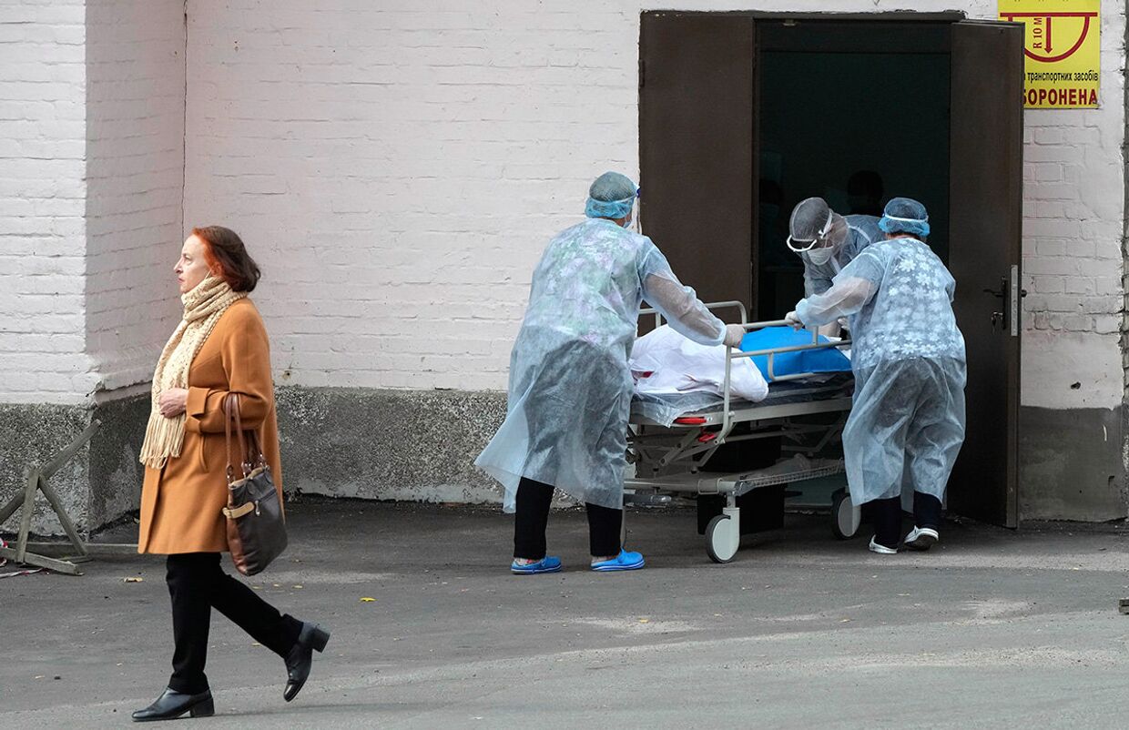Медицинский персонал выносит тележку с пациентом из инфекционного отделения COVID-19 в городской клинике в Киеве