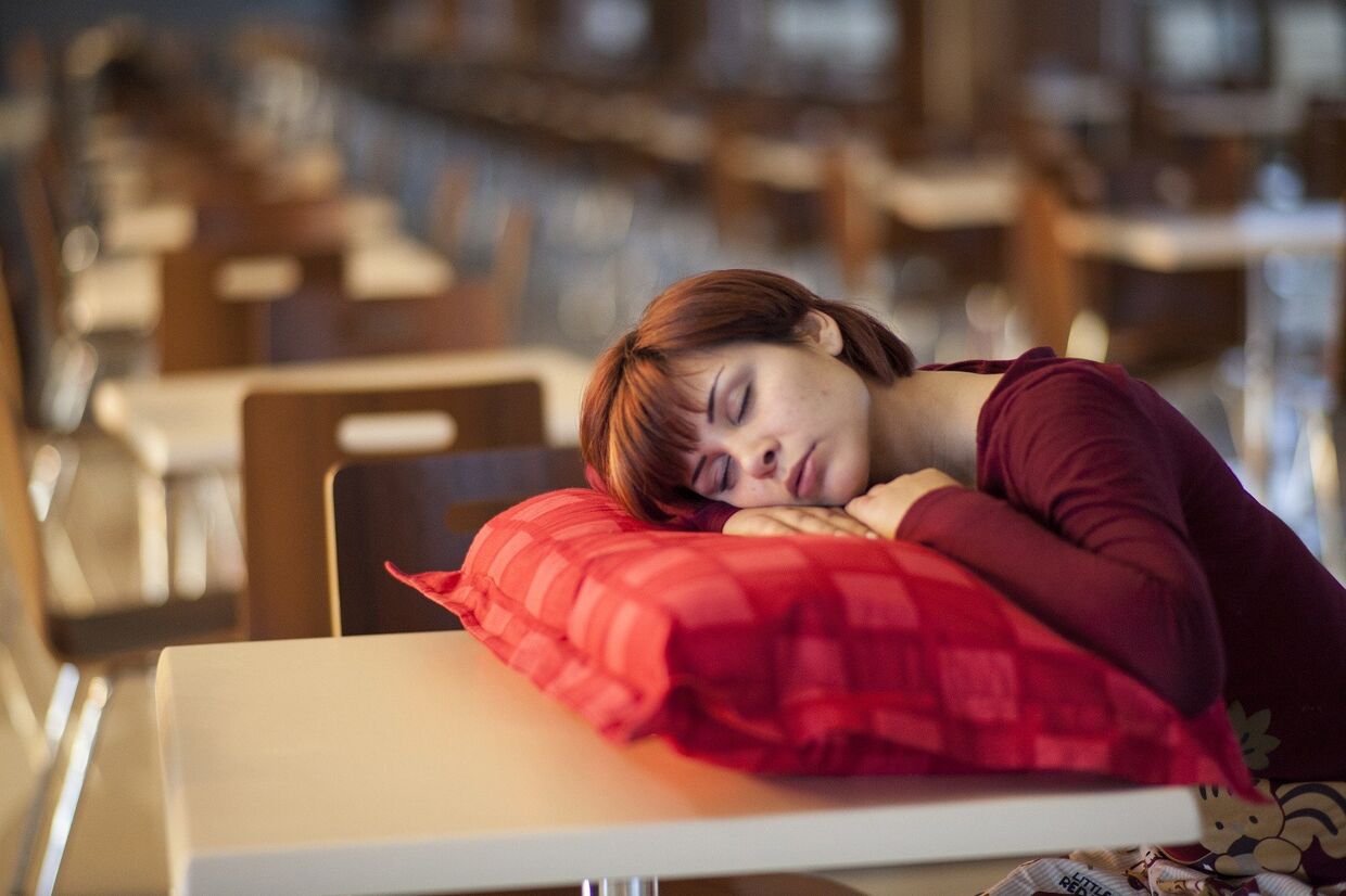Девушка спит за столиком в пустом кафе