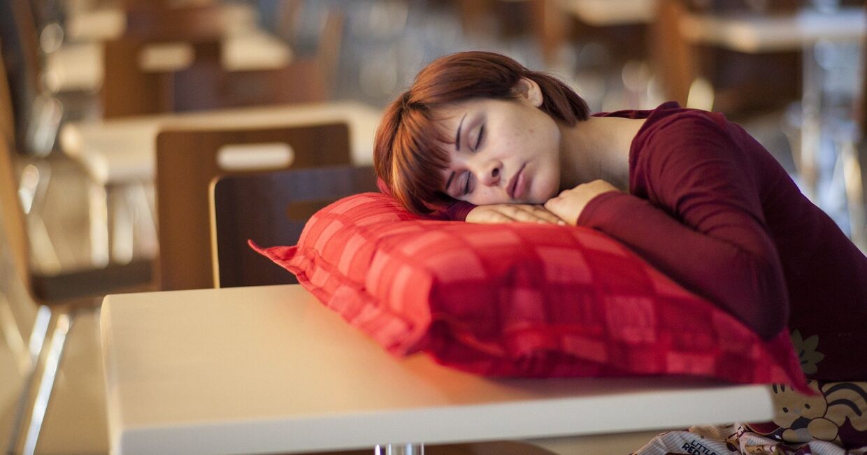 Девушка спит за столиком в пустом кафе