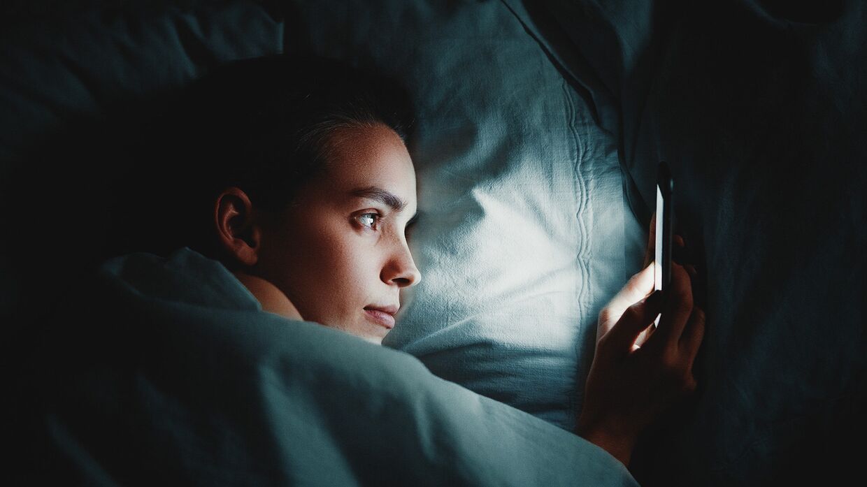 Девушка пользуется смартфоном в постели